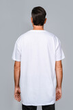 Fototapeta Dinusie - Man dressed in a white oversized t-shirt with blank space, ideal for a mockup, set against gray background