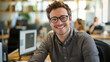 © Mangevigne - Cool worker with glasses smiling at the camera in a busy office