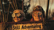 © Y_Malashkevych - Two spirited seniors wearing goggles in a hot air balloon with a 'Still Adventuring' sign, lifelong exploration, for inspiring senior travel or promoting adventure experiences for the elderly