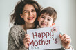 © mittpro - Beautiful smiling young mother with her son holding a sign that says happy mother's day.