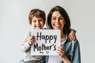 Beautiful smiling young mother with her son holding a sign that says happy mother's day.