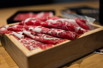 Wall Mural - Premium rare slices wagyu beef with high marbled texture on square wooden plate served for Sukiyaki and Shabu