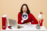 Fototapeta  - Young mad employee business woman wear red sweater sit work at office desk with pc laptop hold megaphone scream announces sale Hurry up isolated on plain beige background. Achievement career concept.