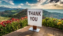 A "Thank You" Sign Stands Amidst Blooming Flowers With A Captivating Mountainous Horizon, Perfect For Gratitude Appreciation Themes.