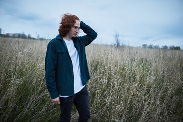 thoughtful man with red hair in overcast field