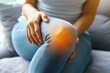 Health care of knee pain concept, close up hand of woman arthritis sitting joint ache, sore cramp or sprain tendon in leg on sofa at home	