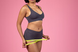 Fototapeta  - Woman measuring waist with a bright yellow tape measure