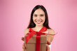 Happy woman offering a gift with red bow