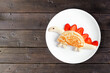 Cute child theme breakfast pancake in the shape of a dinosaur. Top down view on a dark wood table background.