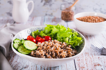 Poster - Bowl with buckwheat, cucumber, cherry tomato and lettuce on the table for a healthy lunch