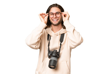 Wall Mural - Young photographer man over isolated background with glasses and surprised