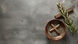 Ash Wednesday, faith, liturgy, religious ceremony background. Wooden cross, ceremonial dish with ash and olive branch on gray background