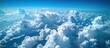 This aerial view shows fluffy clouds below as seen from an airplane window, emphasizing the vast expanse and beauty of the atmosphere.