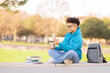 Casual student browsing phone with coffee, studying at park