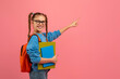 Student girl pointing sideways on pink backdrop