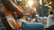 Closeup young man playing guitar among friends attend a live music event concert in a park