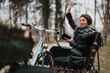 © qunica.com - An elegant young woman in stylish outfit works remotely on her tablet in a serene park setting.