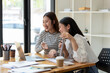 © Wasana - Two engaged businesswomen discussing a business report Share insights and ideas in the office, Remote work with virtual meeting presentation in office.
