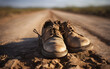 A pair of worn-out shoes on a dusty road, symbolizing journey and endurance, with a defocused sunrise or sunset in the background