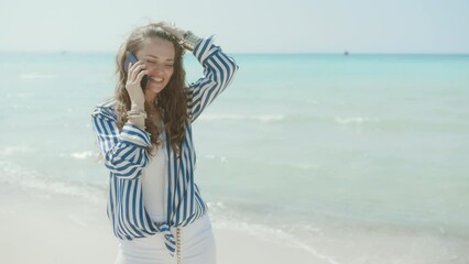 Wall Mural - happy stylish middle aged woman on the seashore speaking on a smartphone.