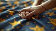   A tight shot of two hands clasped together on a blue and yellow bedspread