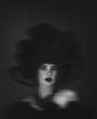 A dramatic black and white portrait of a mysterious woman with dark makeup, lush curly hair, and a sultry gaze against a shadowy background.