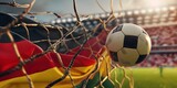 Fototapeta Natura - Close up of football ball in the net of goal of stadium on the german flag background. Football europe championship in Germany wide banner concept.