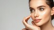© Matt - Portrait of a glamorous model applying cosmetics cream to her face against a grey studio background, skincare advertisement with large space for text