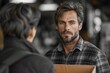 © Larisa AI - An adult male engages in a serious conversation, with a blurred figure in the background Focus is on his intense gaze