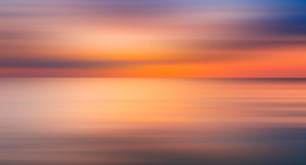 Poster - Abstract sun is setting over the ocean, casting warm glow on water. The sky is filled with clouds, creating a moody atmosphere. reflection of sun on water is a beautiful sight to behold, motion blur.