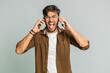 Irritated nervous stressed Indian young man talking screaming on two mobile phones having conversation conflict quarrel complaint dispute discuss solve problem. Arabian guy isolated on gray background