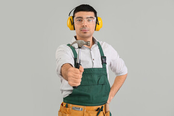 Sticker - Young carpenter with hammer on grey background