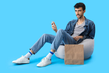 Sticker - Handsome young man using mobile phone on blue background