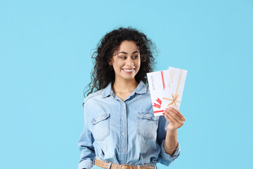 Poster - Young African-American woman with gift cards on blue background