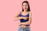 Fototapeta Panele - Young woman pointing at applied medical patch on her arm against color background
