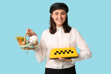 Wall Mural - Happy female driver with Easter basket and taxi roof sign on blue background