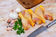 Home cooking. Fresh raw chicken drumsticks and condiments prepared for roasting on wooden table