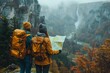 © Good Shot - Two hikers with yellow backpacks stand overlooking a grand waterfall in an autumn-hued valley, consulting a map.