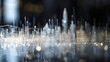 A conceptual depiction of an abstract cityscape is made from tiny glass sculptures, each depicting skyscrapers and streetlights, all connected by thin wire chains against a dark background.