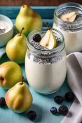 Wall Mural - Delicious chia pudding yogurt with pear sauce and pear in glass jar on a pastel background, summer dessert.