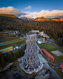 Fototapeta Londyn - Strbske Pleso, Slovakia - Aerial panoramic view of the sightseeing tower by Strbske Lake with the High Tatras at background on an autumn afternoon at sunset with warm sunlight, blue sky and clouds