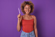 Young beautiful inspired African American woman teen raises pen up wanting to answer teacher question or saying that there is idea for weekend stands in purple studio. Schoolgirl, teenager, student