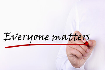 A person writes text, a word, the phrase Everyone Matters with marker on a light background. Business concept.