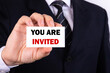 © PRO Balance - Businessman shows a sign with the text YOU ARE INVITED. Business concept