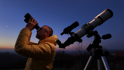 Wall Mural - amateur astronomer looking at the evening skies, observing planets, stars, moon and other celestial 