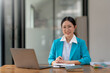 © amnaj - Charming asian businesswoman sitting working on laptop in office.