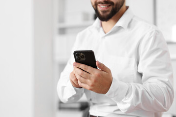 Poster - Young man using smartphone in office, closeup. Space for text