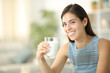 Happy woman smiling at camera holding a glass of milk