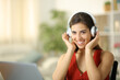 Happy woman wearing headphone looks at camera at home
