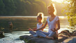 A woman and her daughter practice yoga on the river bank. The connection between mind and body